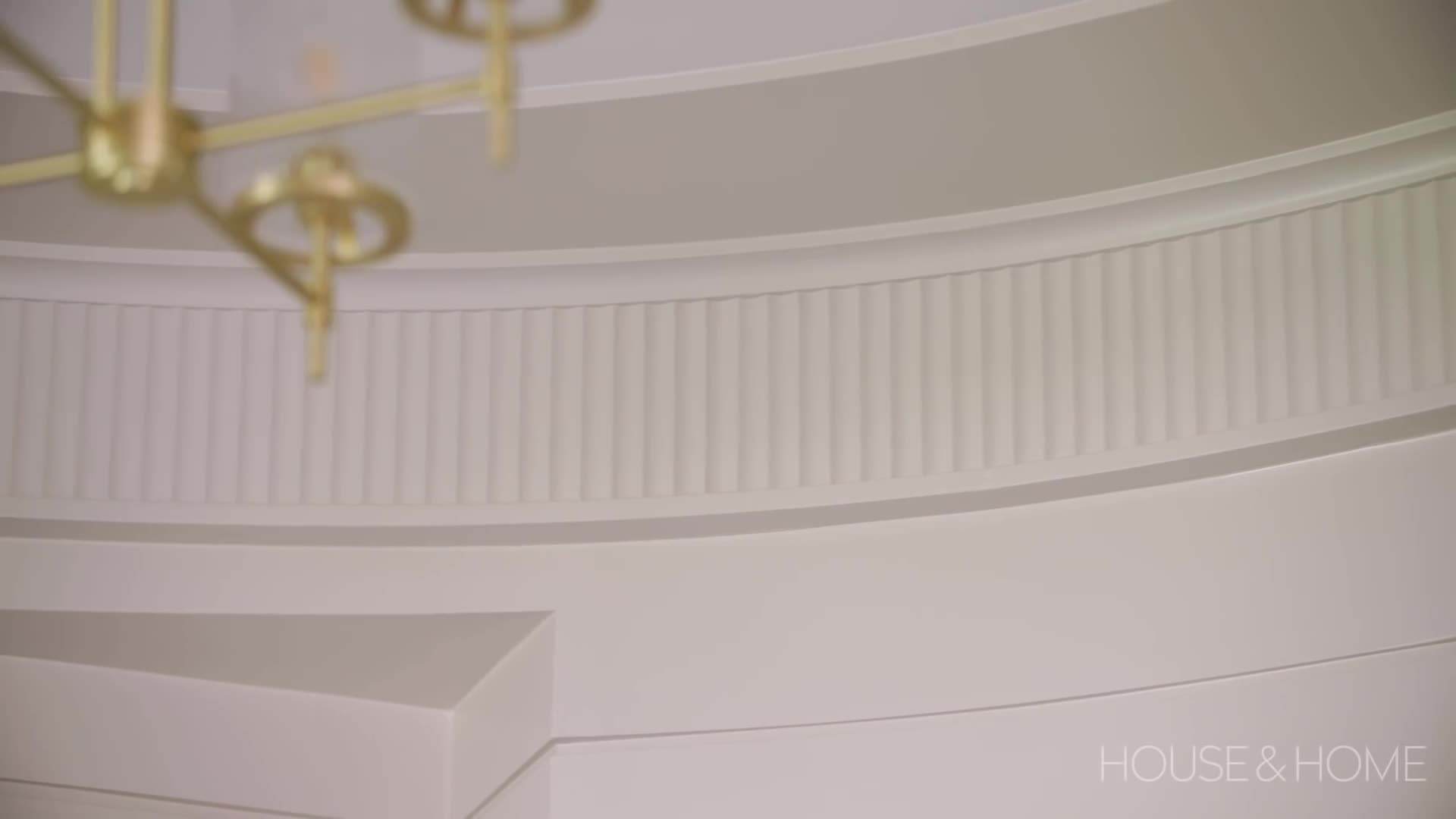 The luxurious living room features high ceilings, a statement chandelier, and plush furnishings.