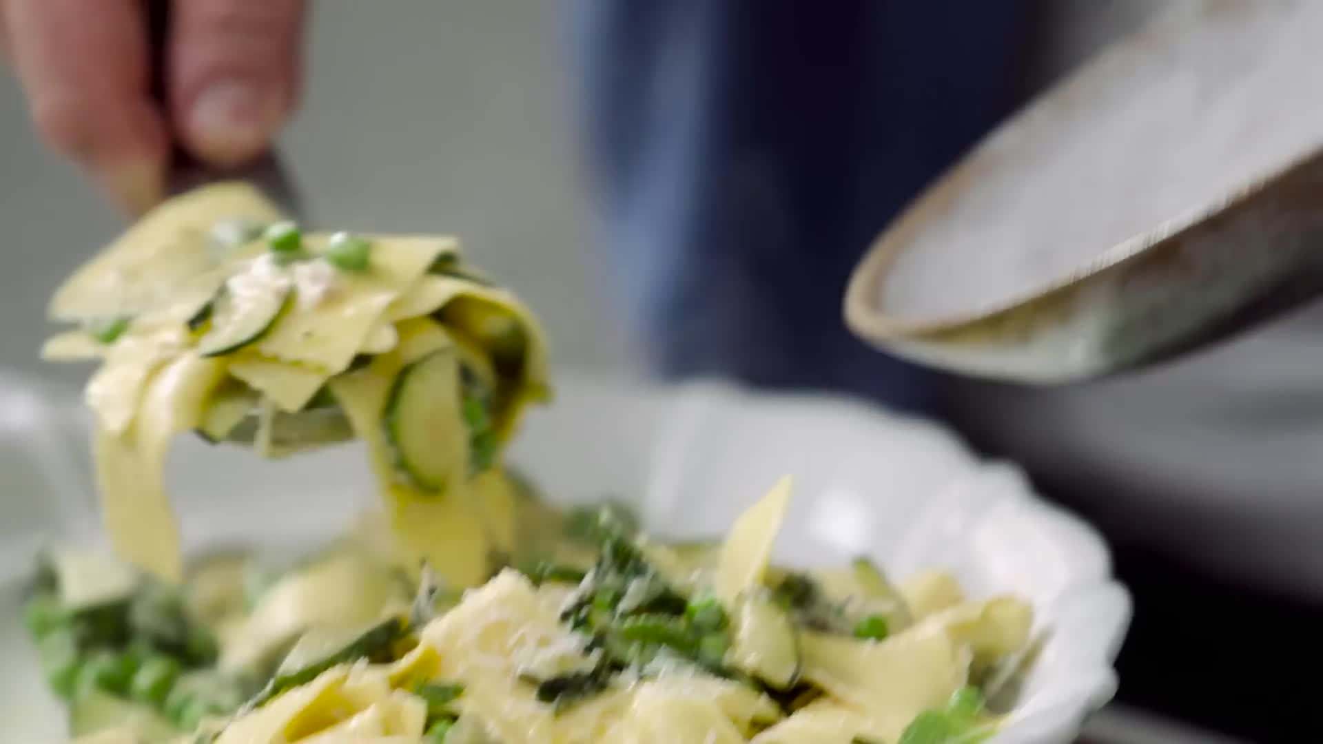 Tossing the pasta with the creamy sauce and vegetables