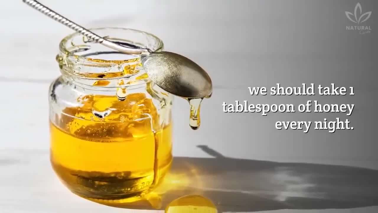 A jar of honey with a spoon next to a cup of herbal tea