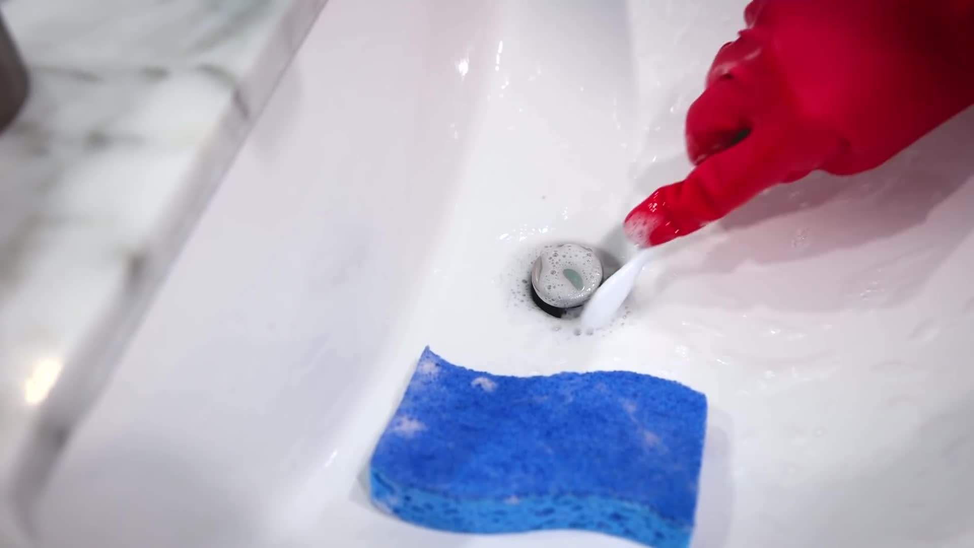 Using a microfiber cloth to clean the sink