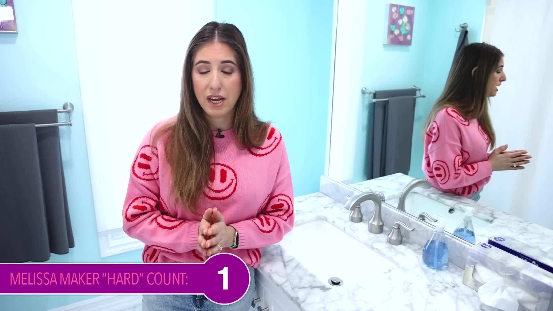 A person using a handheld steam cleaner to clean the bathroom tiles