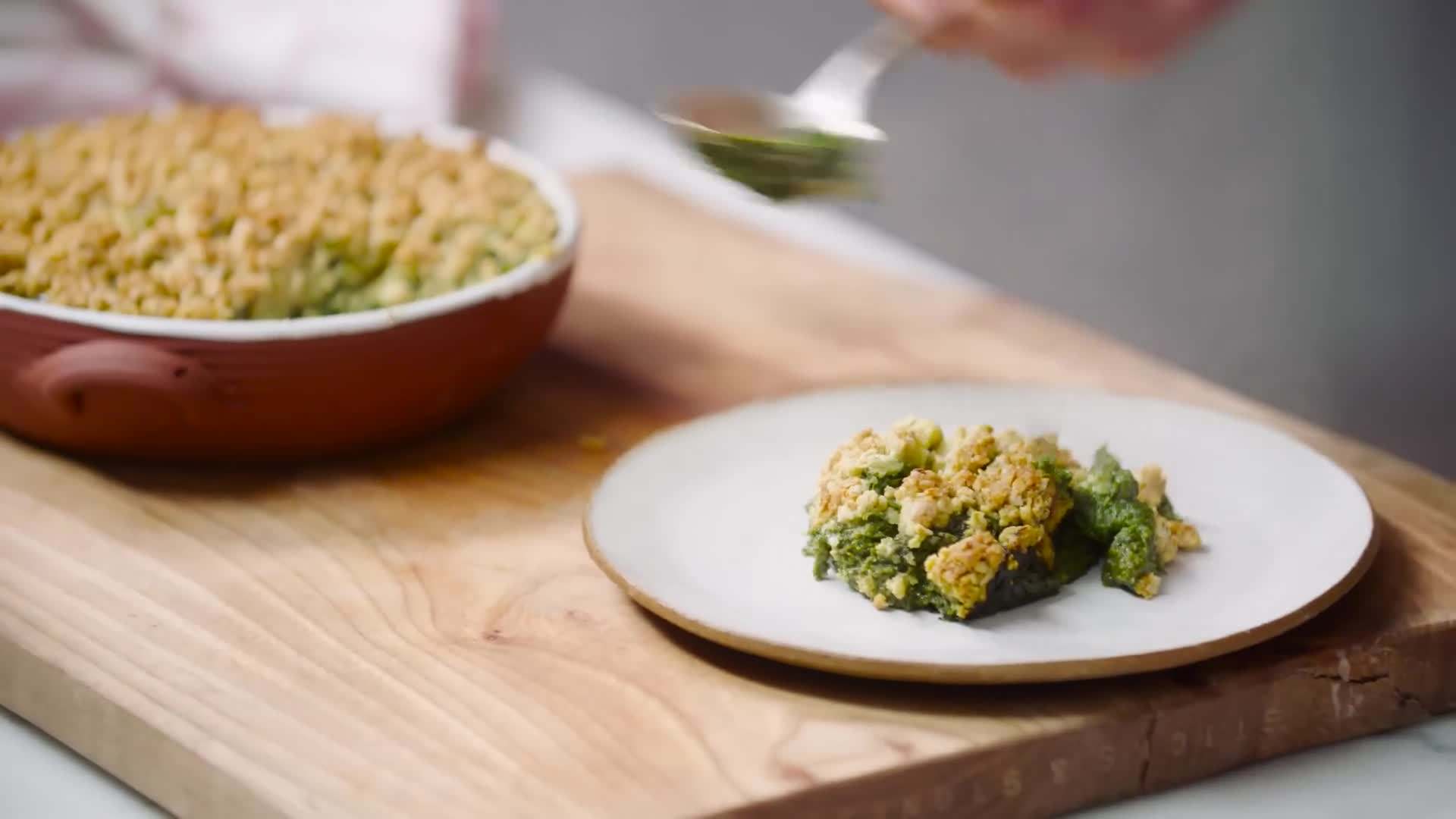 Crunchy breadcrumb topping being sprinkled over the creamed spinach