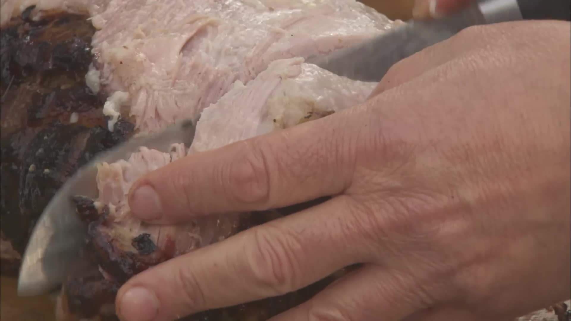 Slicing into the juicy and tender porchetta, revealing the flavorful meat