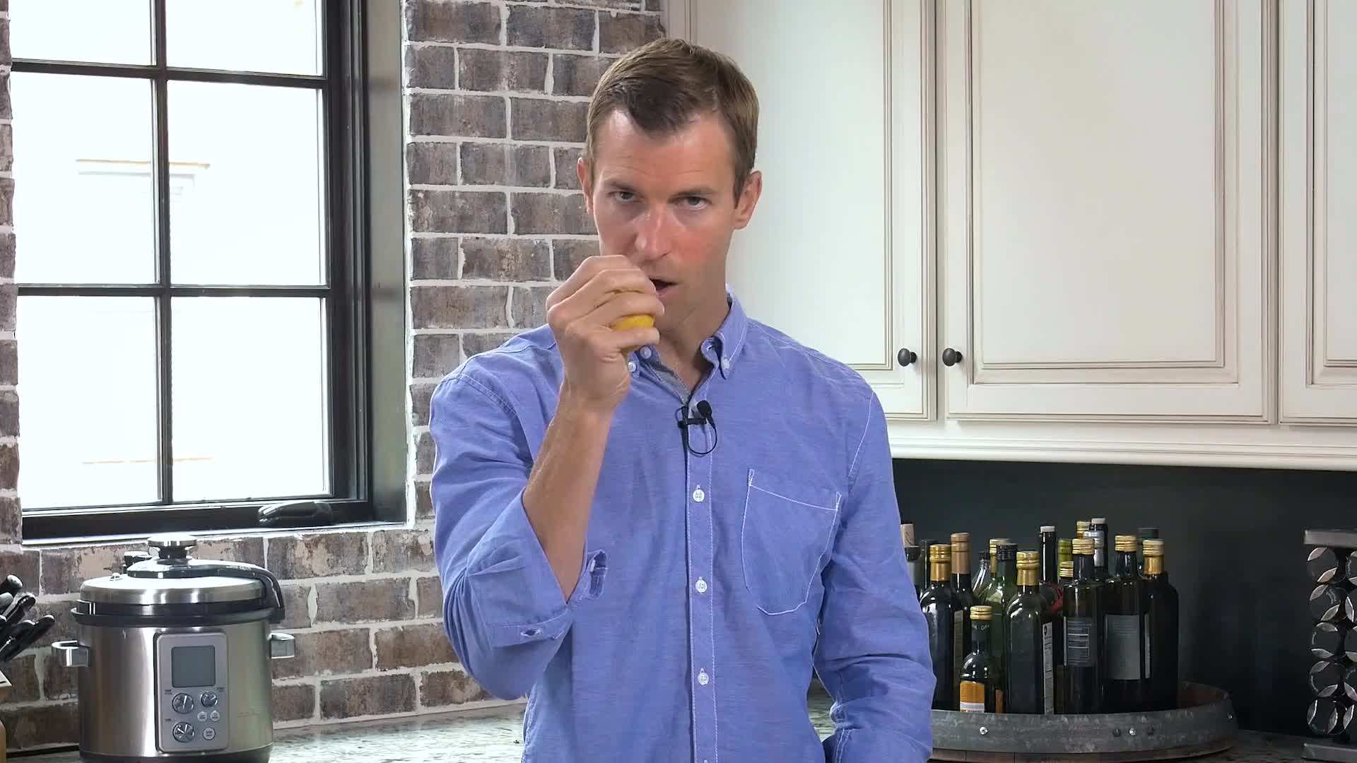 Lemon being squeezed into a glass of water